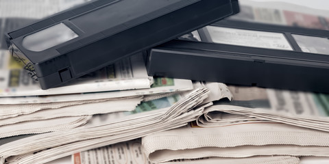Old video cassette and newspapers, daily news concept. Panoramic image.
