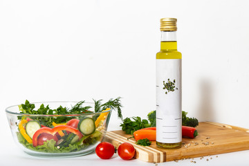 Composition with hemp oil and vegetables: cherry tomatoes, sweet peppers, lettuce leaves, dill and Basil leaf on a light background.