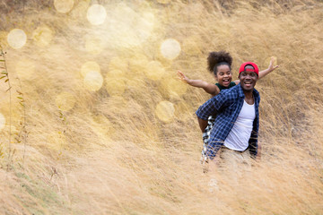 beautiful happy african american father and daughter happy and smiling on hay or dry grass. African American family playing together in the outdoor park