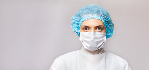 portrait female doctor in a protective mask and a medical cap on a gray background. copy space. space for text or logo