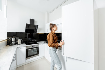 Woman looking into the fridge, standing on the modern kitchen at home
