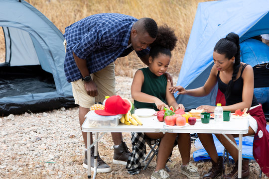 Family Enjoying Camping Holiday. Family interacting while having fruit and solf drink outside the tent at campsite - Powered by Adobe