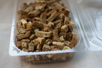 crackers are in a plastic container from the store for salad beer snacks with garlic and cereals from rye bread with seeds