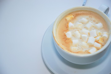 White cup of cappuccino coffee with small marshmallows and brown froth