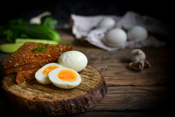 Boiled Chicken Eggs. Healthy breakfast in the village. Wood background. Dark photo. Free space for text. Cucumbers, wooden cutting board.