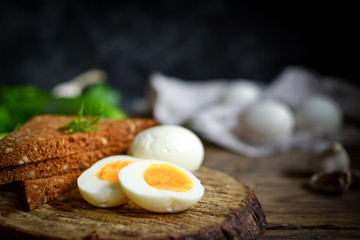 Boiled Chicken Eggs. Healthy breakfast in the village. Wood background. Dark photo. Free space for text. Cucumbers, wooden cutting board.