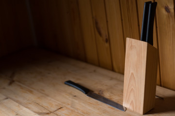 Fototapeta na wymiar Wooden background. Kitchen interior. Kitchen utensils in blur. Knife in blue. Wooden interior in country house. Knife block on wooden table.