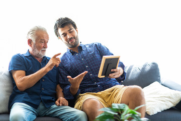 Fototapeta premium Father and son family time together at home concept. Happy old father and son sitting together and looking photos while remembering old times past.