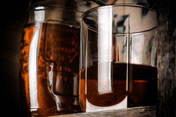 Glass cup and bottle with alcohol on the bar shelf.