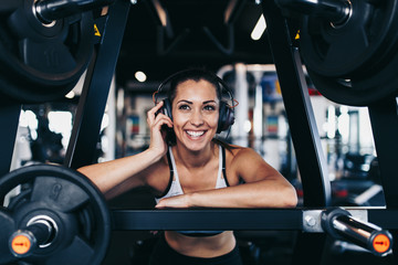 Young attractive woman after successful workout in modern fitness gym dancing, smiling and singing....