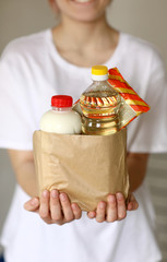 Volunteer with a package for donations with products. Hands of a young girl holding a bag of food