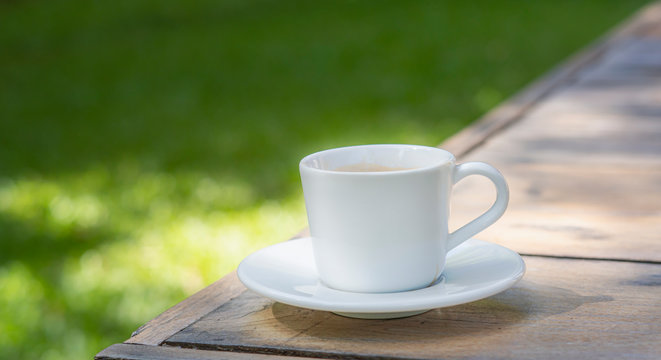 white coffee cup place on plank wood table in morning,Soft light.