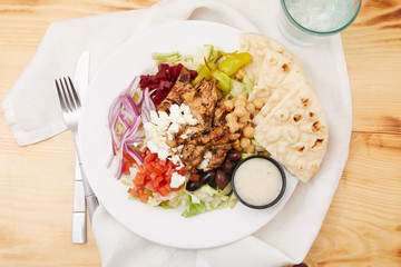 A classic greek salad featuring chicken, feta and pita