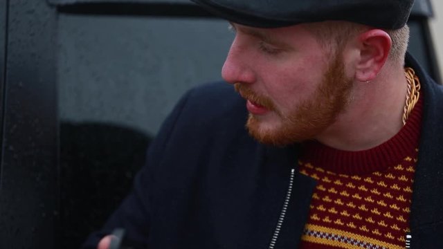 A guy with a red beard is talking and twirling a brass knuckles in his hands