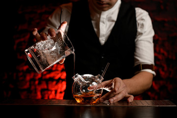 Close-up bartender pours cold drink into designer flask