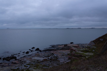 The rocky shore and fortifications of the Suomenlinna island in the Gulf of Finland and a view of the islands in autumn twilight in Finland. The harsh and laconic beauty of Finnish nature.