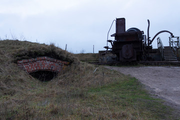 Fototapeta premium The case and the turning mechanism of a large old cannon from the time of the Russian Empire near fortifications in the historical fort Suomenlinna, in Helsinki, Finland, autumn day