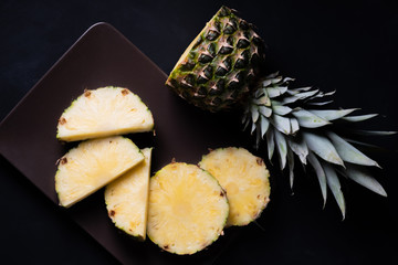 sliced pineapple on a black background in low key