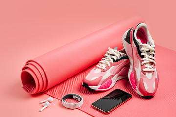 Bright fashion sneakers with smartphone, fitness bracelet and pink yoga mat. App for training...