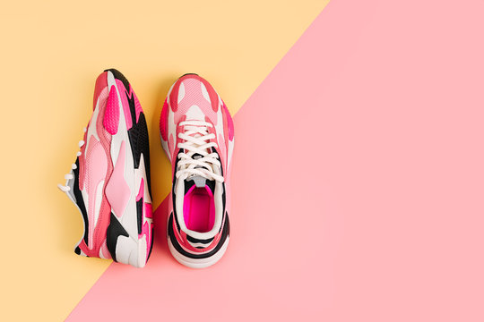 Bright female sneakers on pink background. Fashion blog or magazine concept. Women's shoes, trendy sneakers, fashion, style, lifestyle. Flat lay top view copy space minimal background..