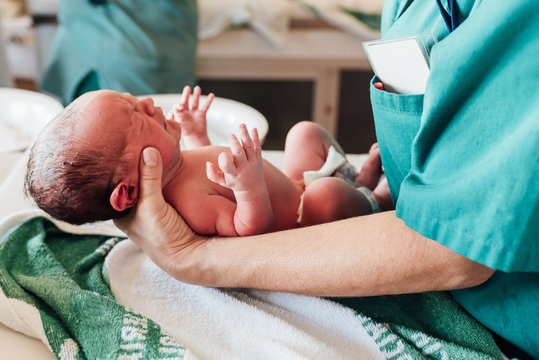 Doctor treats a newborn baby he's holding in his hands