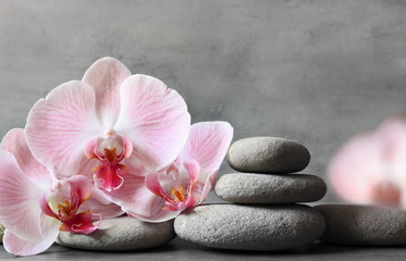 Spa stones and pink orchid on the grey background.