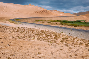 bend of a road on a hill through the yellow desert in northern Iceland