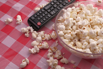 high angel view of popcorn in a bowl and tv remote on table.