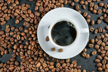 Cup of aromatic coffee and roasted coffee beans close-up. Top view.