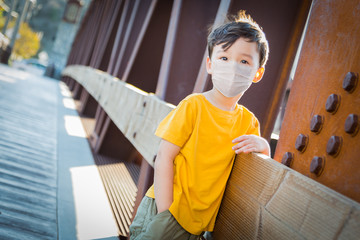 Young Mixed Race Chinese and Caucasian Boy Playing Alone Wearing Medical Face Mask Outside