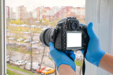 Close-up of hands holding a camera to take a photo from a house window. Quarantine, health concept.