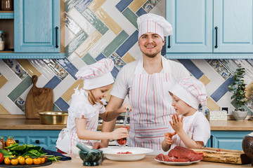 Happy family in the kitchen. Father and children prepare food together in the kitchen at home. The concept of cooking.