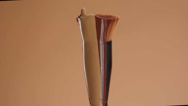 a round foundation brush with a liquid foundation for a deep skin tones covering it. Cosmetics for a deep skin tones