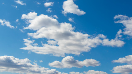 Naklejka na ściany i meble White clouds of unusual shape in the blue sky on a beautiful day