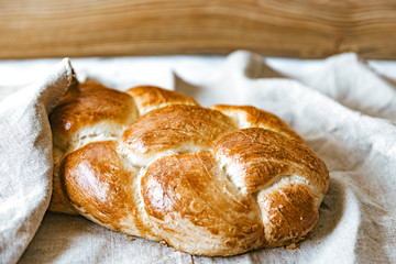 Homemade Jewish traditional challah bread on linen tablecloth. Top view of warm fresh baked challah