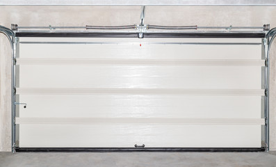 Closed white garage door with electric drive, view from the inside.