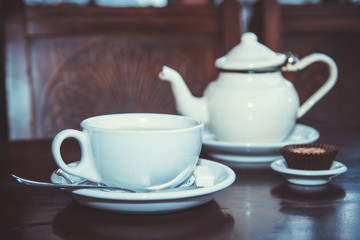 White teapot and a cup of tea at the cafe. Selective focus. Vintage style.