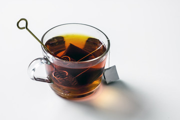 Transparent cup of tea with honey spoon