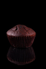 Chocolate muffin on a black background. Chocolate muffin in paper on a black background.