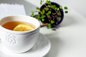 Obraz na płótnie Canvas White cup of tea with lemon slice close-up. Homemade cozy tea