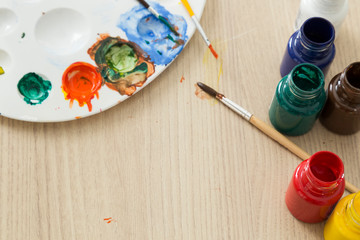 colorful paints with brush on the wooden table