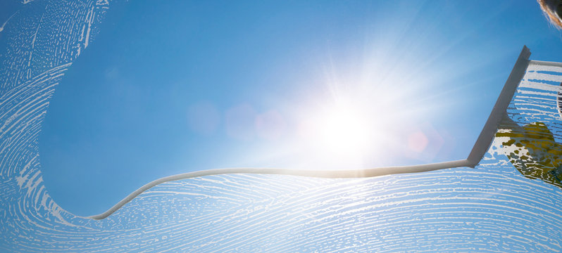 window cleaner cleaning window with squeegee and wiper on a sunny day