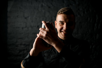 Portrait of smiling bartender which holds steel shaker.