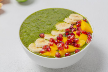 Green smoothie bowl with banana, kiwi, mango and pomegranate. Healthy breakfast