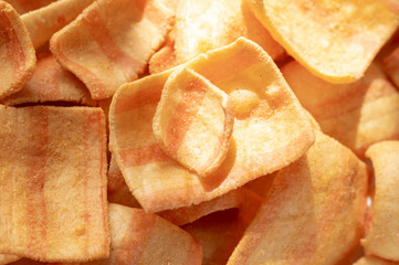 Square chips with bacon. Macro photo of chips. Sunbeam for food.