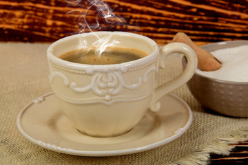 A retro style mug full of black coffee next to white sugar in a bowl