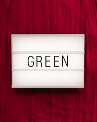 Lightbox with the word "Green" on a intense red background to express a contrast; complementary, flat lay