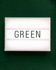 Lightbox with the text "green" on a dark green background; flat lay