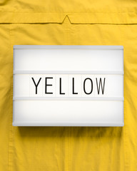 Lightbox with the text "yellow" on a intense yellow background; flat lay