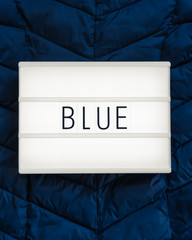 Lightbox with the word "Blue" on a dark blue background; flat lay